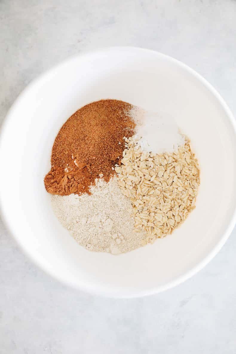 Dry ingredients for apple muffins in a large white mixing bowl.