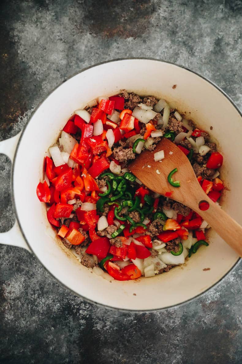 Beef and veggies in a white dutch oven.
